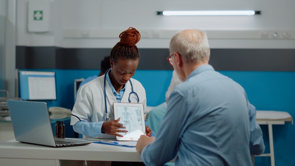 Healthcare specialist looking at digital tablet with old patient